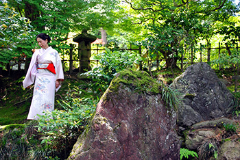 Woman wearing a Kimono walking through the gardens of Japan